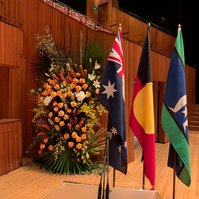 Susan Avery’s floral arrangement beside the Australian, Aboriginal and Torres Strait Islander flags at the Sydney Opera House