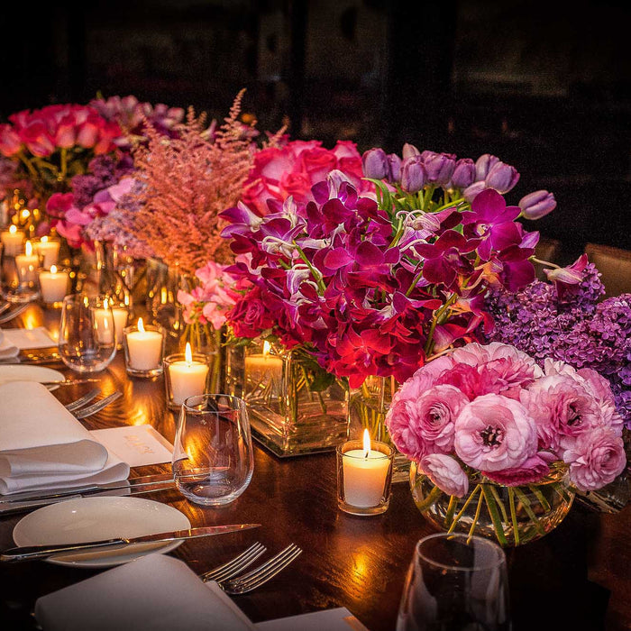 Pink and purple flowers with candles along a wedding dining table