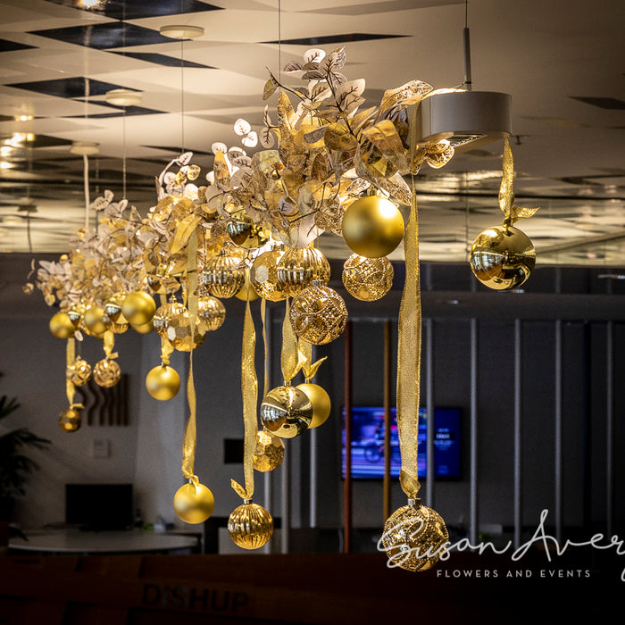 Gold baubles and metallic foliage suspended in an office Christmas installation