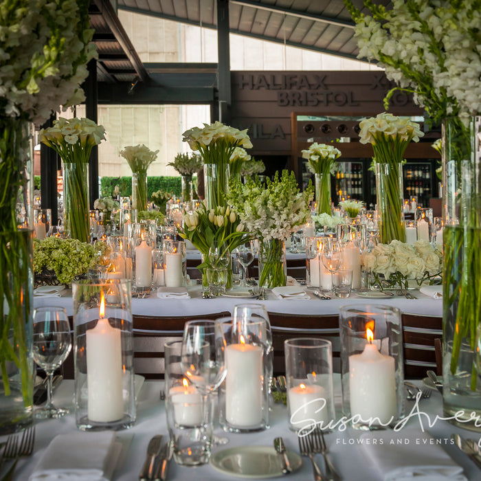 White flower arrangements in clear glass vases with candlelight at Cafe Sydney