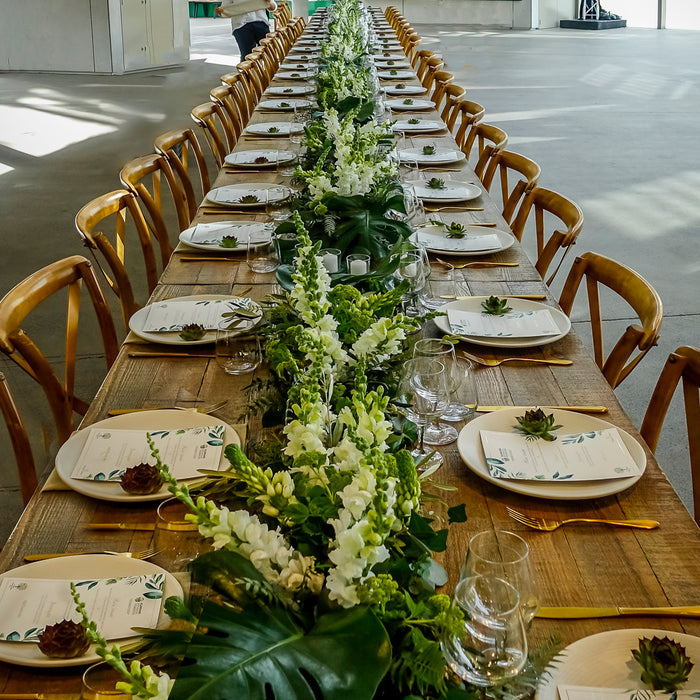 Long corporate dining table with white flowers, greenery and timber chairs at The Calyx
