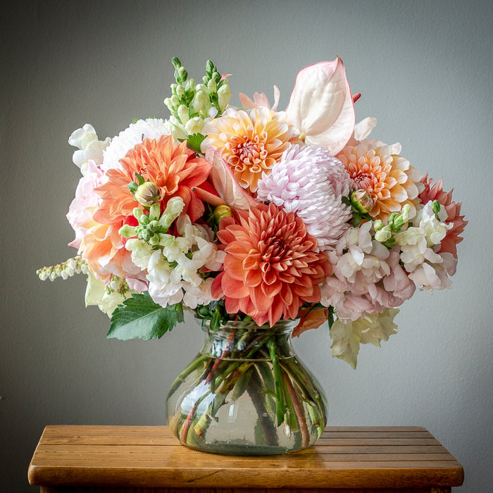 Vase arrangement showing the wedding colour palette of pink, cream, peach and orange